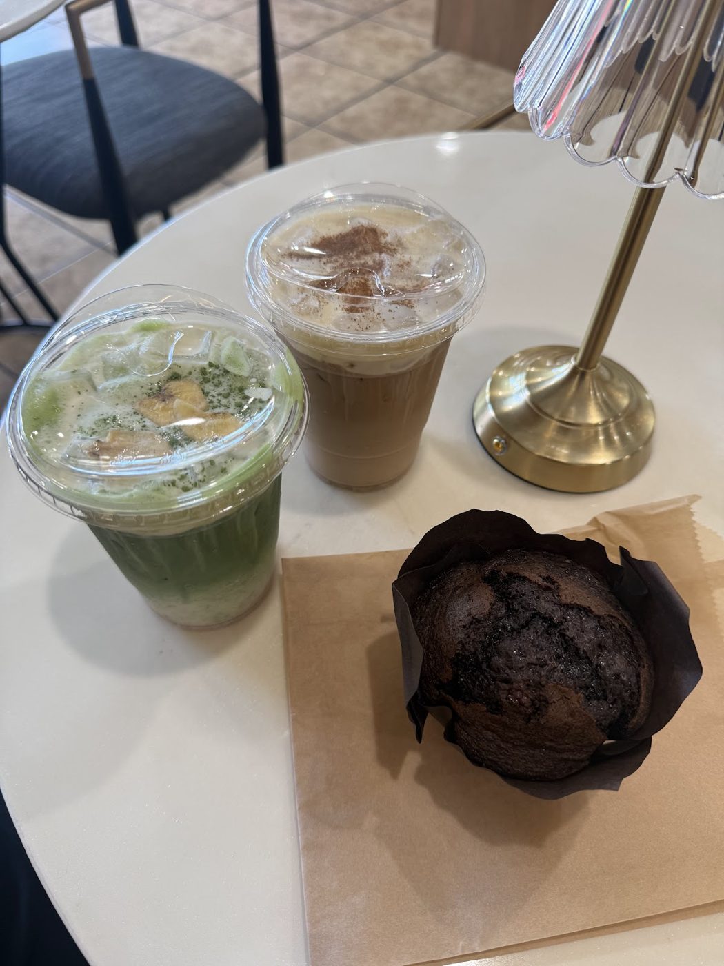Iced matcha, a latte and a muffin on a marble table